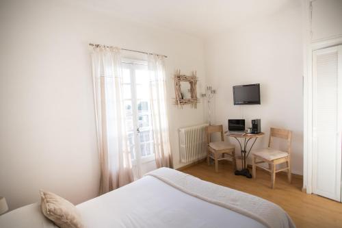 a white bedroom with a bed and a table and chairs at La Regalido in Fontvieille