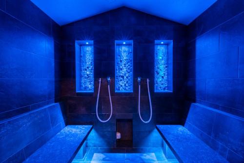 a blue bathroom with two benches and a shower at Hotel B&B Feldmessner in Brunico