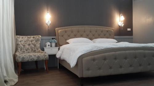a bedroom with a large bed and a chair at Baan JaoKorKluay บ้านเจ้ากอกล้วย in Chiang Rai
