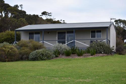 a house with a green lawn in front of it at Tidal Dreaming Seaview Cottages in Yanakie