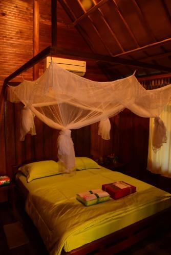 a bedroom with a bed with a mosquito net over it at Sunari Beach Resort 2 in Selayar
