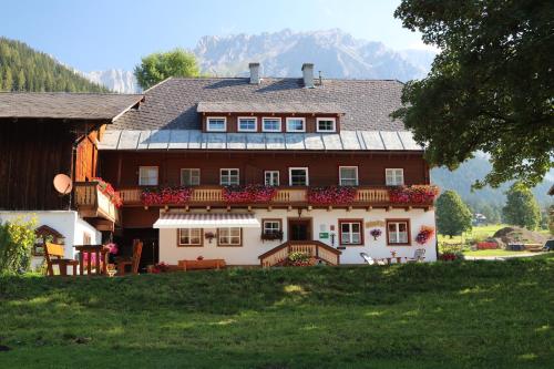 duży dom z czerwonymi kwiatami przed nim w obiekcie Zeiserhof w mieście Ramsau am Dachstein