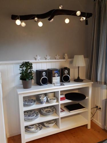 a white shelf with speakers and plates and a lamp at Blockhausperle im Grunen in Oldenburg