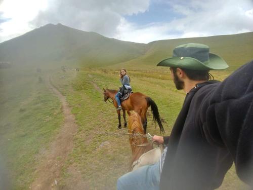 Una donna che cavalca un cavallo in un campo con un uomo di Levan & Megi a Jut'a