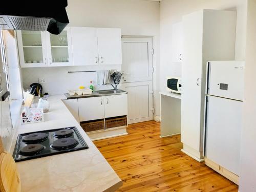 a kitchen with white cabinets and a white refrigerator at Cosy Private Cottage in Port Elizabeth