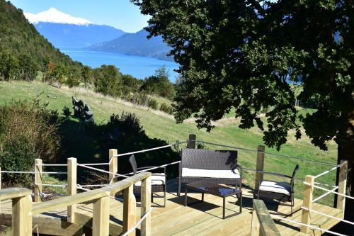 a wooden deck with a bench and a view of a lake at Las Bandurrias Eco Hostal in Cochamó