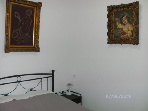 a bedroom with two pictures on the wall and a bed at Nina Rooms (apartments) in Artemida