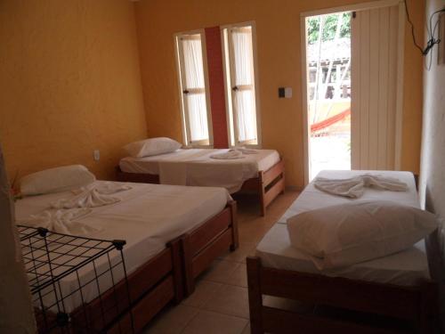 um quarto com três camas e uma janela em Hotel Pousada Castanheiras do Village em Porto Seguro