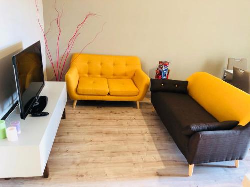een woonkamer met een gele bank en een tv bij SL Apartament in San Gregorio di Catania