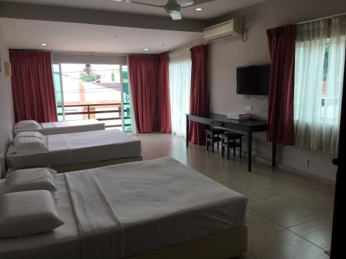 una camera d'albergo con 3 letti e una scrivania di Meng Meng GuestHouse a Kuantan