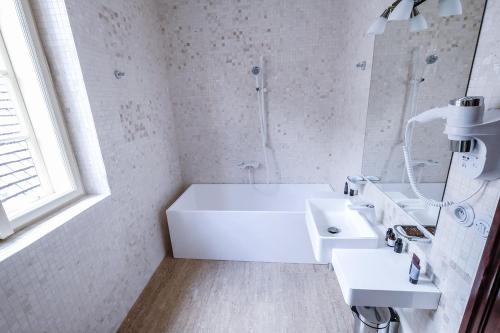 a white bathroom with a tub and a sink at Hotel Ebersbach in Český Krumlov