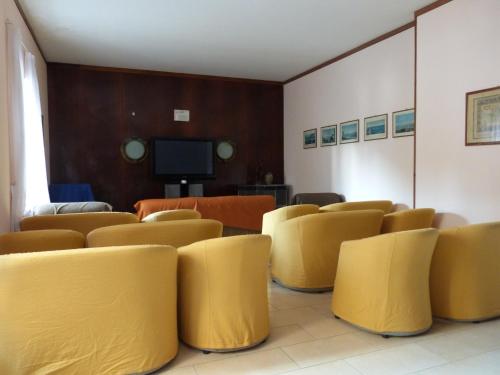 a waiting room with yellow chairs and a tv at Hotel Savoy in Varazze