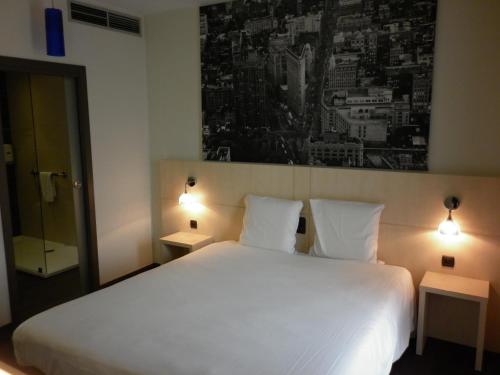 a bedroom with a large white bed with two lamps at Ibis Styles La Louvière in La Louvière