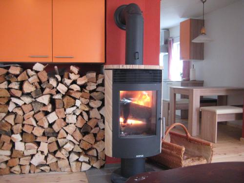 a woodburning stove in a kitchen with a pile of wood at Mandauhaus mit Sauna in Hainewalde
