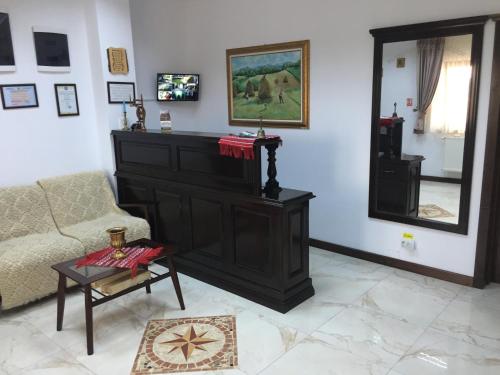 a living room with a couch and a mirror at Pensiunea Zana Muntilor in Piatra Fantanele
