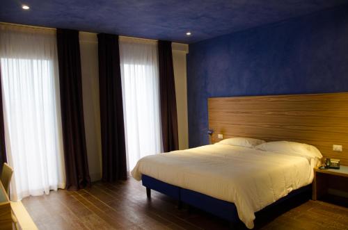 a bedroom with a large bed with a blue wall at Hotel Zodiaco in Porto Cesareo