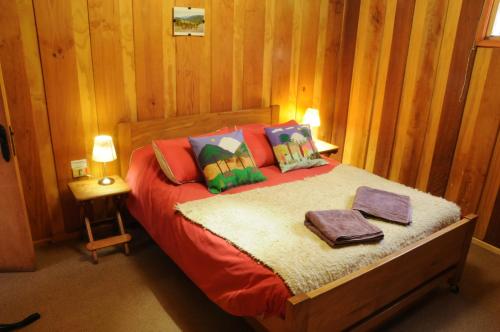 1 dormitorio con 1 cama con paneles de madera en las paredes en Hostal Epu Pewen, en Curacautín