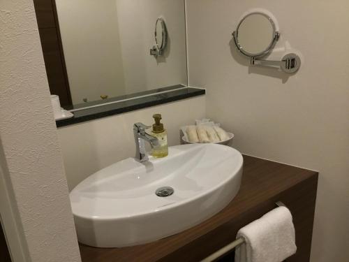 a white sink in a bathroom with a mirror at Sunset Beach Hotel in Chatan