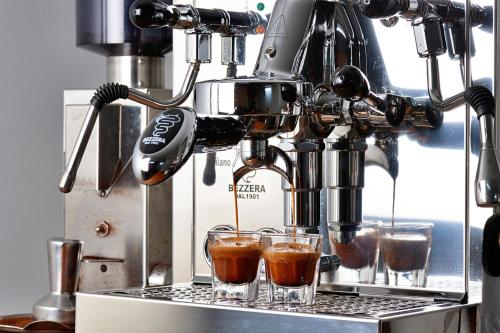 a coffee machine with three glasses on a counter at Sharlynn by the River in Malanda