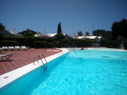 a large swimming pool with blue water in a resort at Relax Bungalows in Maspalomas