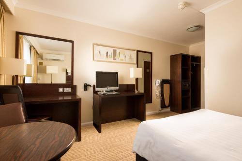 a hotel room with a bed and a desk with a computer at Mercure Norwich Hotel in Norwich