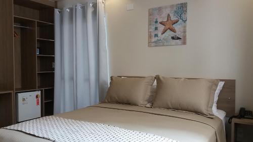 a bed with two pillows and a picture on the wall at Pousada Ilha das Conchas in Guarujá