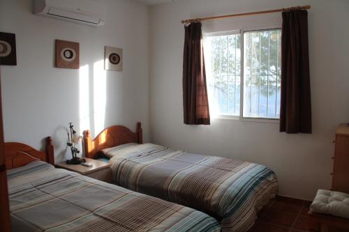2 camas en una habitación con ventana en Casa Soleada Holiday Villa, en Canillas de Aceituno