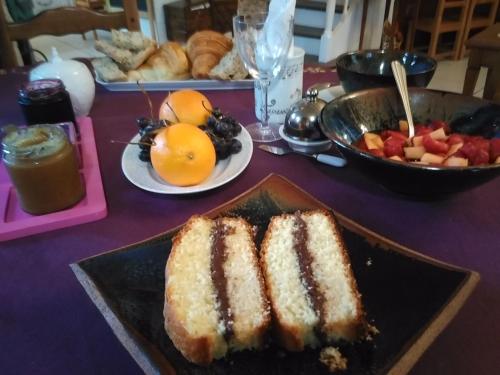 een tafel met een bord cake en een fruitschaal bij La chambre du harpiste in Saint-Mars-la-Jaille