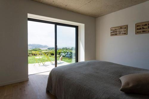 um quarto com uma cama grande e uma janela grande em Maison avec vue mer d'exception et jacuzzi em Penvénan
