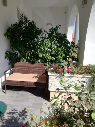 a bench in a courtyard with flowers and plants at Vianova Affittacamere in Giurdignano