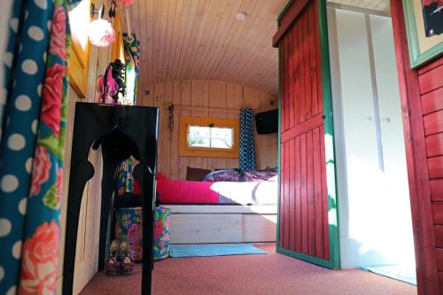 ein kleines Zimmer mit einem Bett und einer Tür zu einem Schlafzimmer in der Unterkunft Roulotte la Dominique in Romery