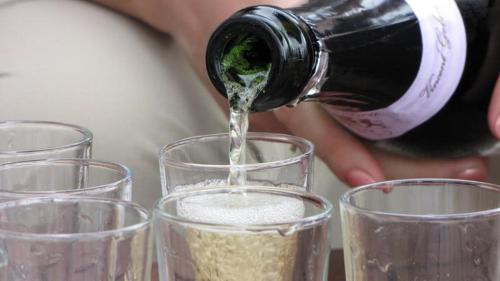 a person pouring a bottle of wine into glasses at Roulotte la Dominique in Romery