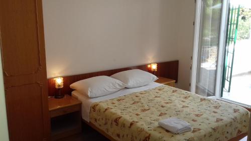 a bedroom with a bed with two pillows and a window at Apartmani Jurin in Primošten