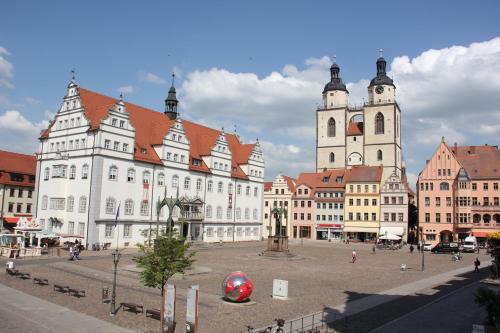 a large white building with two towers in a city at Hotel Cranach-Herberge City Centre in Lutherstadt Wittenberg