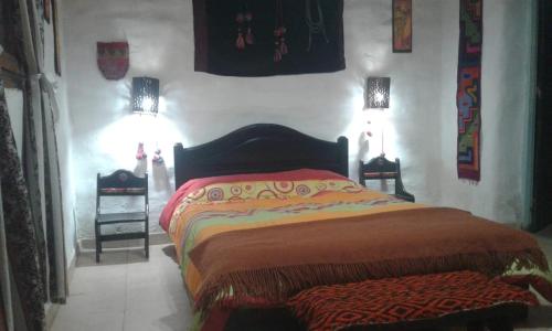 1 dormitorio con 1 cama con 2 lámparas en la pared en Wara Wara en Purmamarca