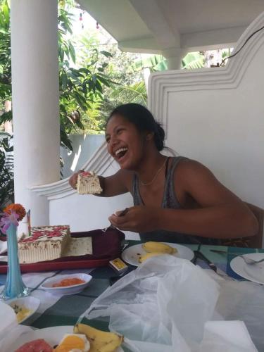 a woman sitting at a table with a cake at Little Angels in Mirissa
