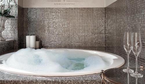 a bathroom with a tub with two wine glasses at Jacuzzi Apartamentai Relaks in Klaipėda