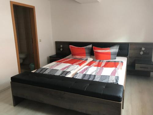 a bedroom with a bed with red and black pillows at Pension "Tor zum Rennsteig" in Hörschel