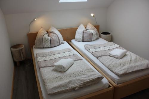 2 bedden in een kamer met handdoeken en kussens bij Jované in Bad Kleinkirchheim
