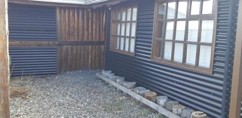 a side of a house with two windows on it at Cabañas y Casa Kauken in Puerto Natales