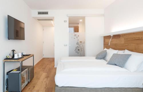 a white bedroom with a bed and a tv at ALEA - Garda Lake Suite in Arco