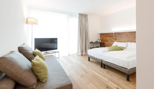 a white bedroom with a bed and a couch at ALEA - Garda Lake Suite in Arco