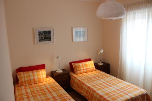 a bedroom with two beds and a window and a lamp at VillasFerrel - Cosy Apartment in Ferrel