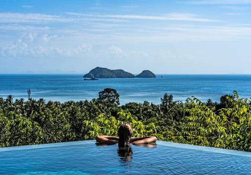 Una mujer en una piscina infinita con vistas al océano en Villa Pandora en Wok Tum