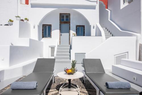 a balcony with chairs and a table and stairs at NK Cave House Villa in Fira