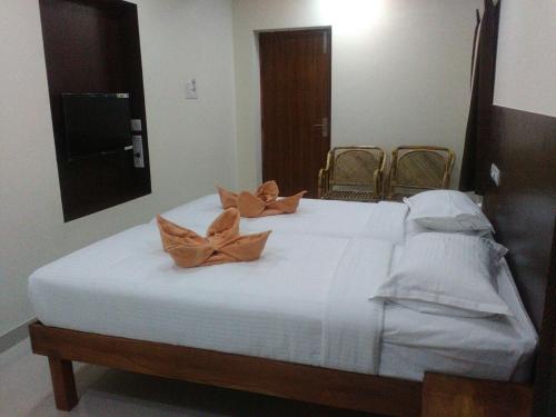 Una cama blanca con dos almohadas encima. en Sri Nivas Guest House, en Mayiladuthurai