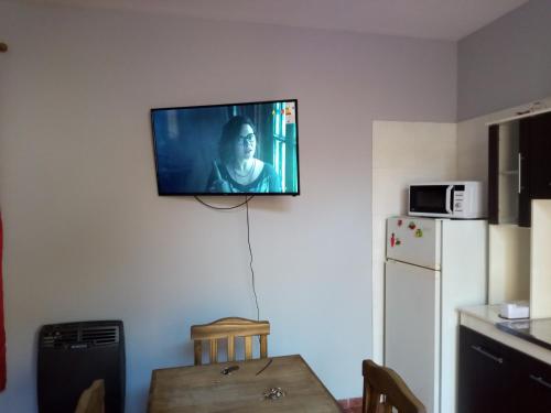 a television on a wall in a kitchen with a table at Los Nietos hospedaje in Mendoza