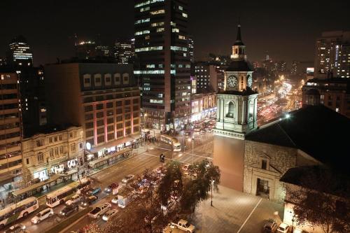 a city skyline at night with a clock tower at Hotel Plaza San Francisco in Santiago