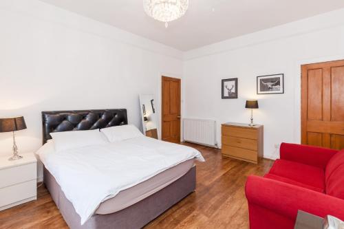 1 dormitorio con 1 cama y 1 silla roja en Old Town Edinburgh Apartment close to Castle and Royal Mile, en Edimburgo