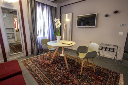 - un salon avec une table et des chaises sur un tapis dans l'établissement Uve Rooms & Wine Bar, à La Morra